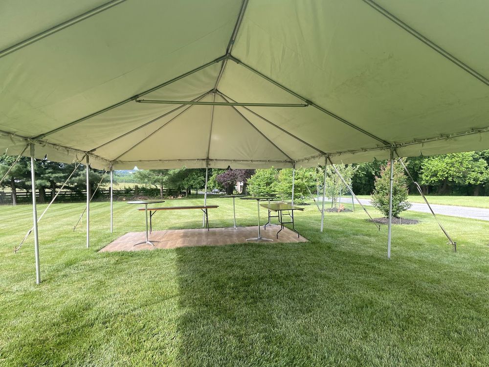 The open interior of a white frame tent on a lawn, showing the frame and clear span